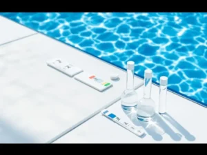 Zwembad met troebel melkachtig water in voorgrond en helder blauw water achteraan, pH-strips en testflesjes op witte rand